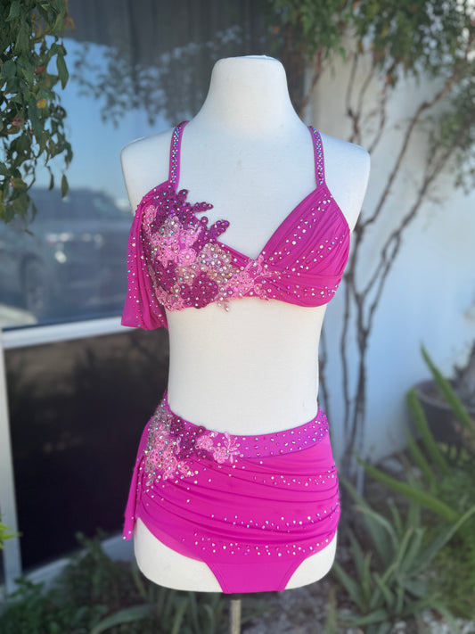 Pink floral lyrical dance costume on a mannequin against a blurred outdoor background