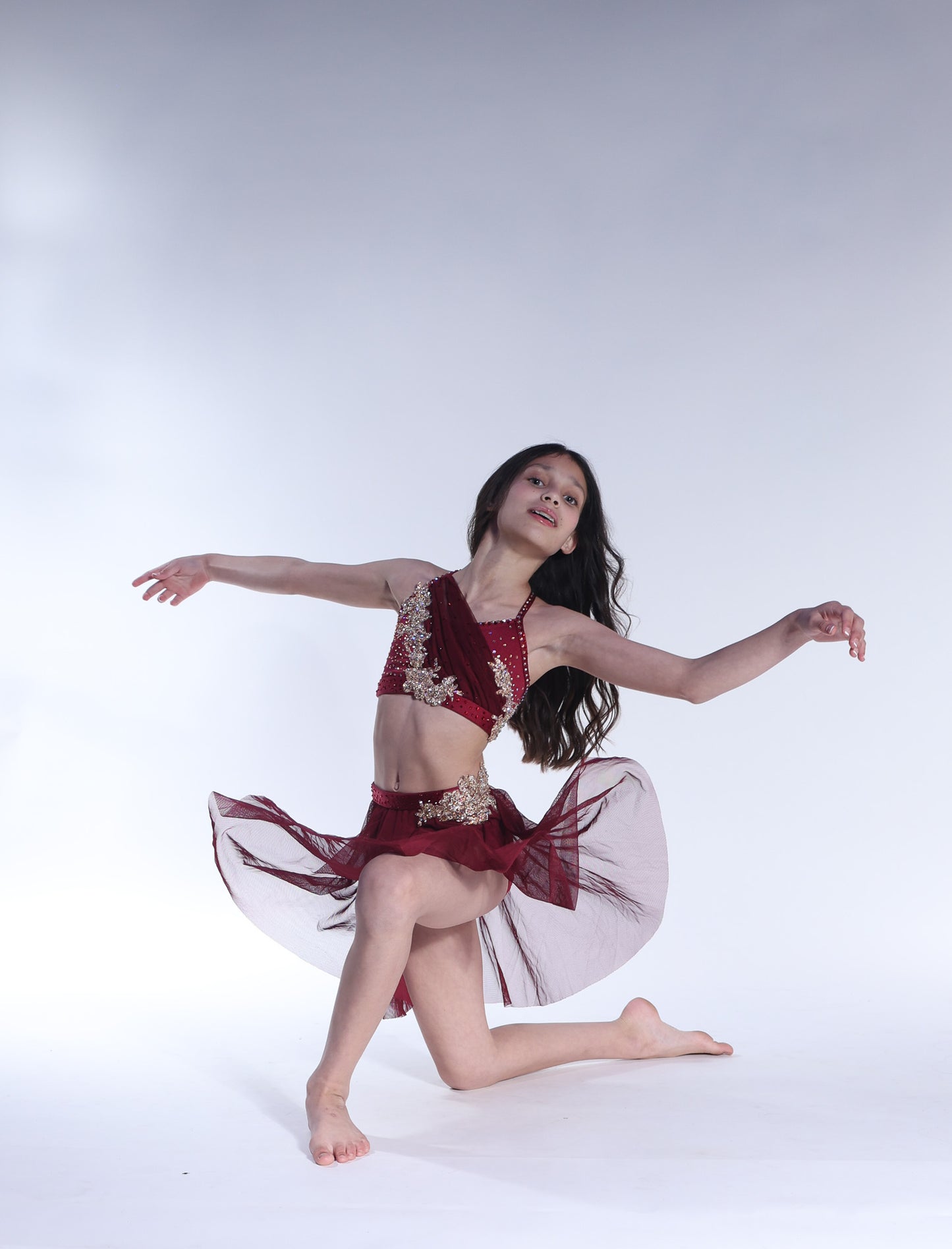 Dancer in a red dance costume with gold accents on a white background