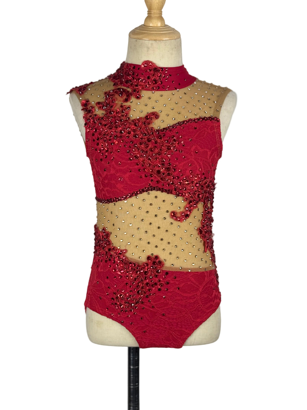 A red and beige dance leotard with intricate beadwork and sequins, displayed on a cream dress form mannequin against a white background.