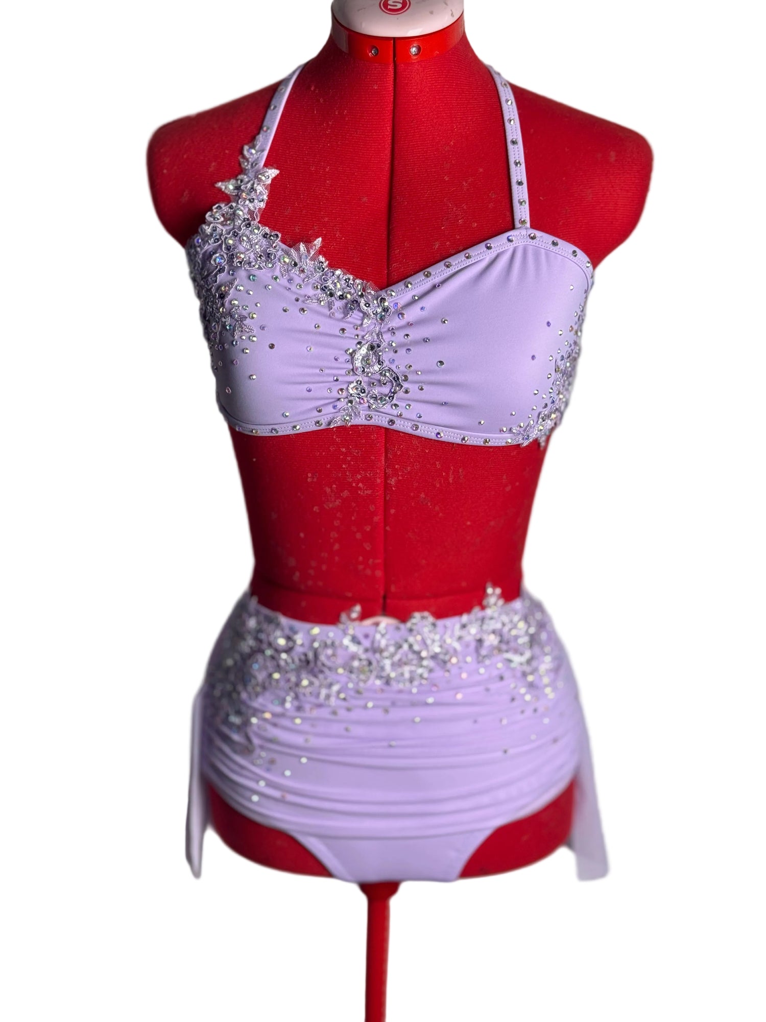Lilac dance costume with silver embellishments on a red mannequin against a white background