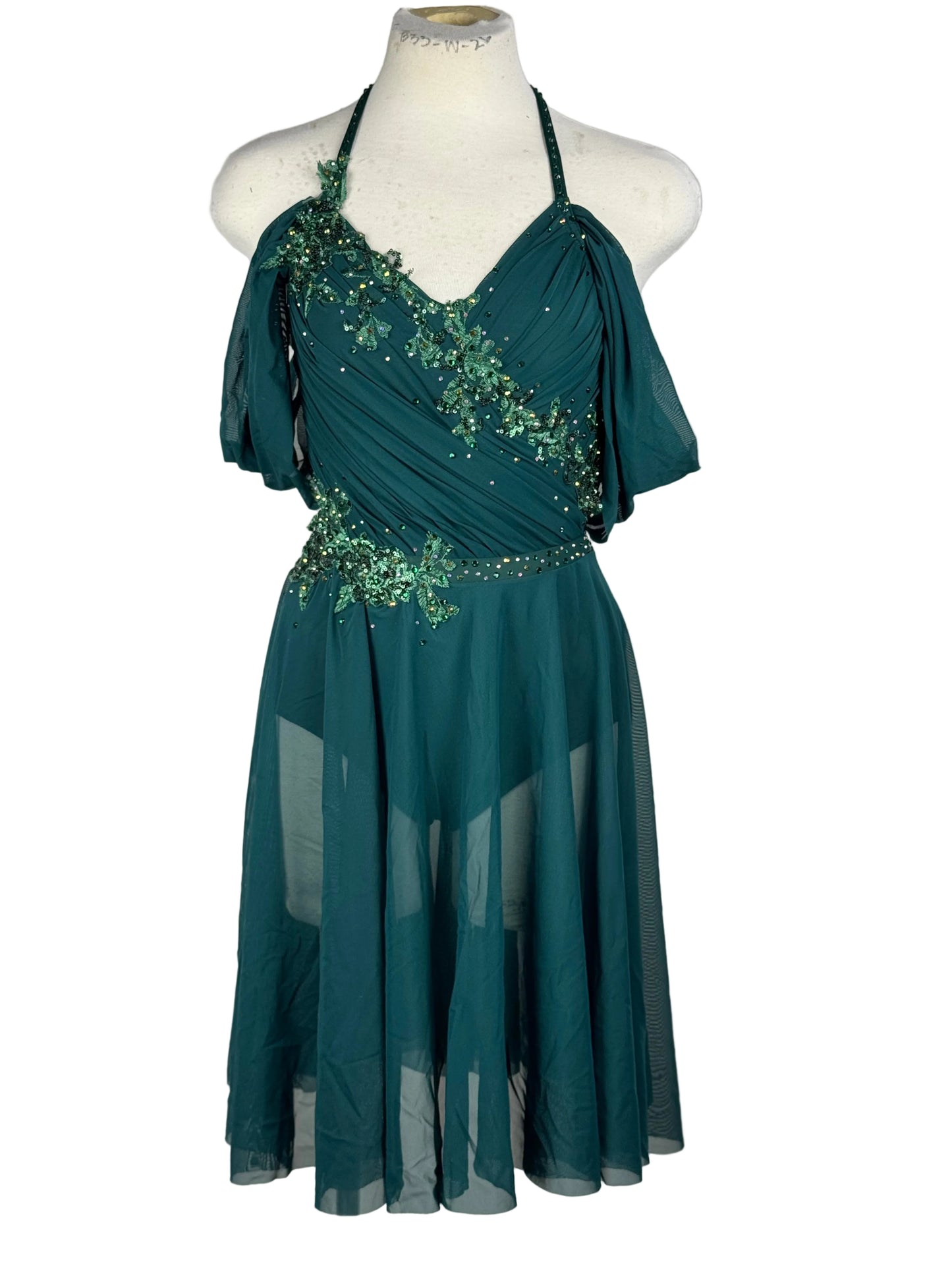 Green lyrical dance dress with embellishments and rhinestones on a mannequin against a white background
