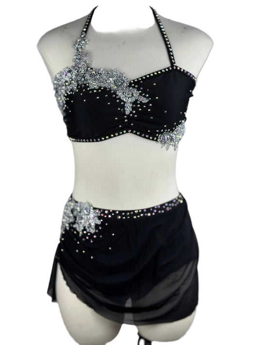 Black and silver lyrical dance costume with beaded top and skirt on a mannequin against a white background